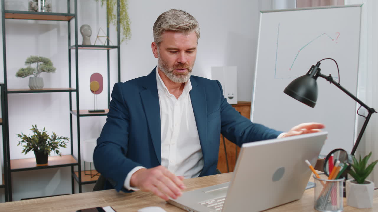 uomo d'affari maturo freelance in ufficio, comincia a lavorare su un portatile, invia messaggi online