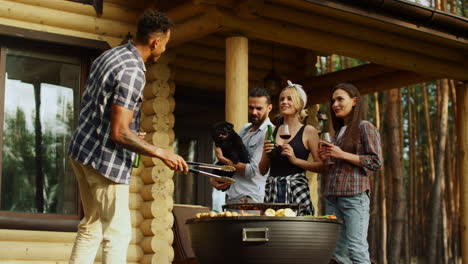 cheerful friends having rest on grill party outdoors. guys clinking glasses