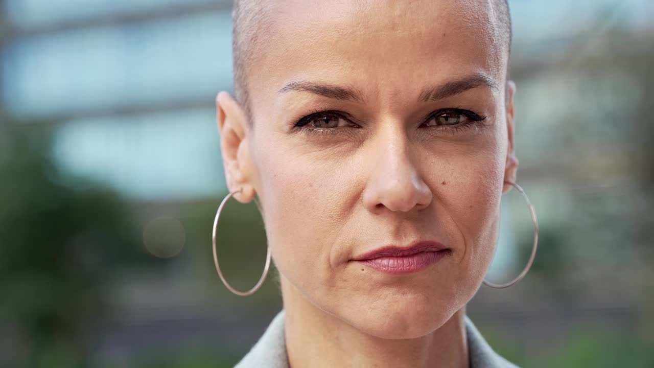 Close up portrait of stylish confident woman with shaved hair. Empowered powerful strong female looking to the camera