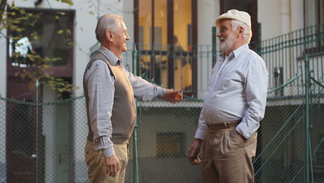 Two-Senior-Retired-Men-Neighbors-Meeting-At-The-Street,-Greeting,-Hugging-And-Then-Posing-With-Smiles-To-The-Camera