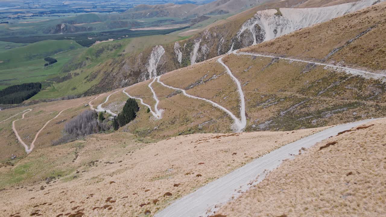 три человека на извилистой дороге, ведущей вверх по сухому, поросшему кустарником склону горы