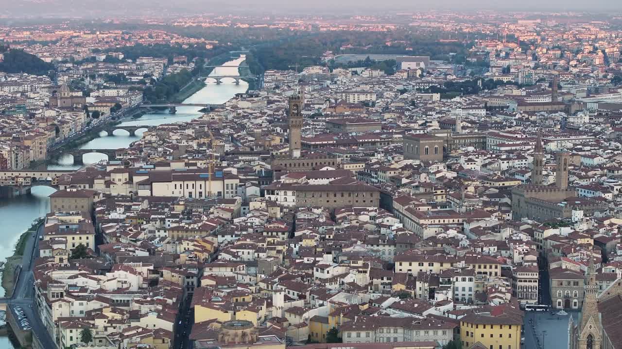 Teleobiettivo ravvicinato della silhouette della cupola del Duomo di Firenze stagliata contro il cielo, mentre il sole nascente spunta da dietro la croce creando un brillante riverbero