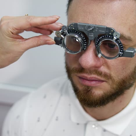 doctor checks man's sight with optical trial frame. portrait of a young male patient testing his eyesight in ophthalmological center