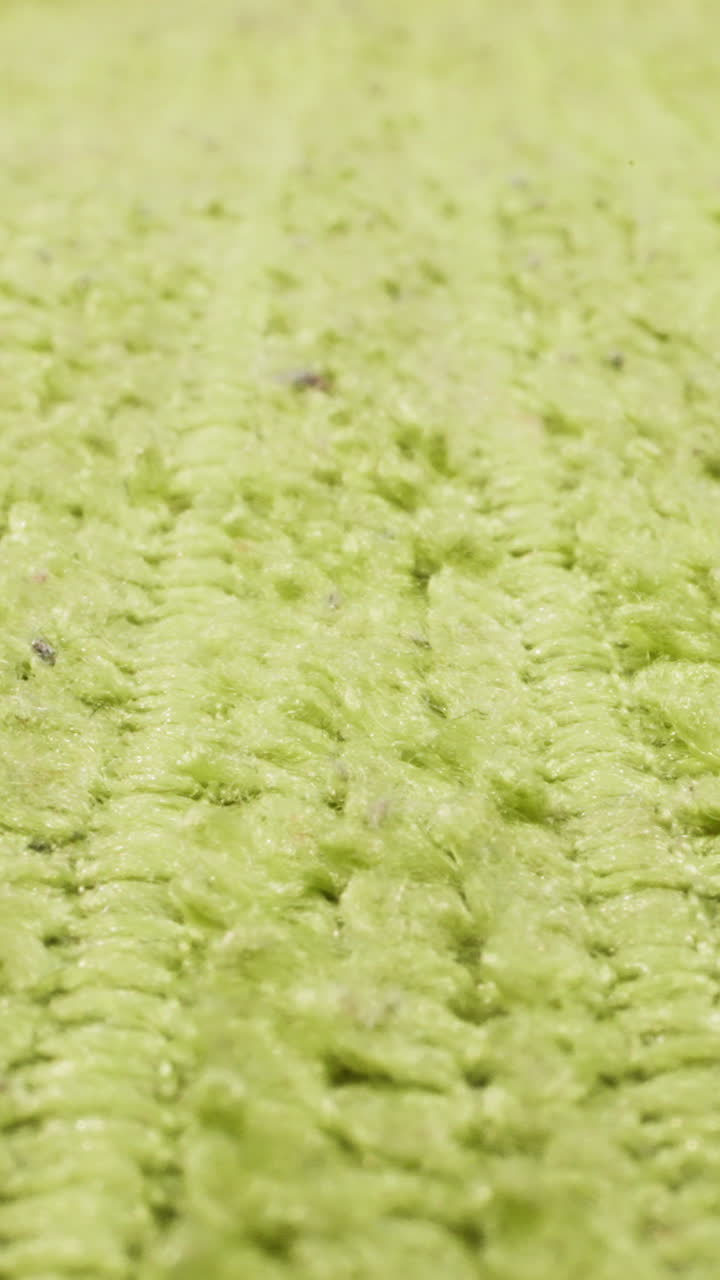 Texture of light green fluffy fabric with seams as background macro view. Colorful cloth sheet with pattern. Plain rag for furniture cleaning