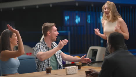 Give-five-joyful-blonde-jumping-with-joy-and-celebrating-victory-and-knocked-out-a-shot.-multi-ethnic-group-of-friends-in-bowling