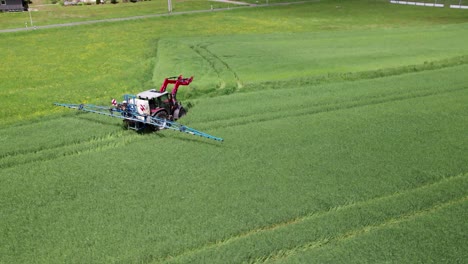 farm worker drives through green field leaving tracks as it goes, aerial