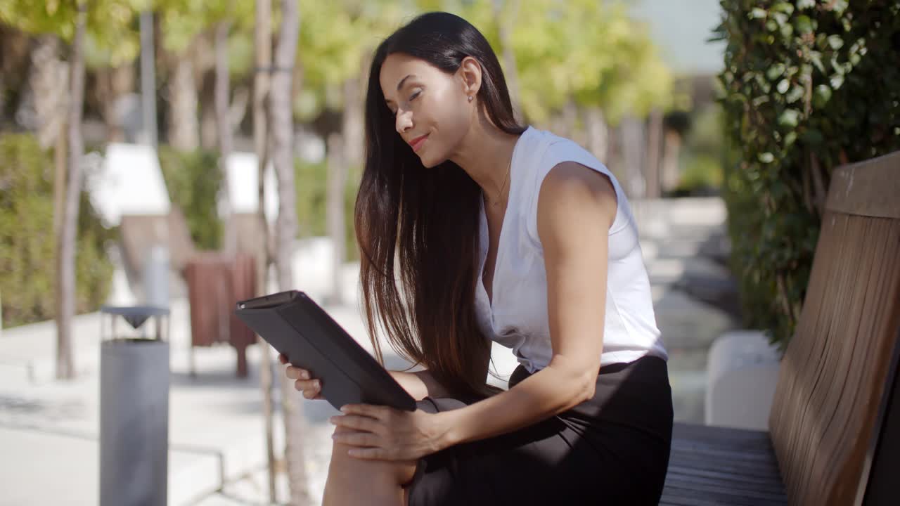 mujer de negocios usando una tableta en un parque urbano