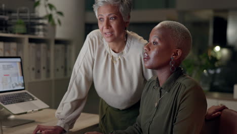 two women collaborating in an office using a laptop