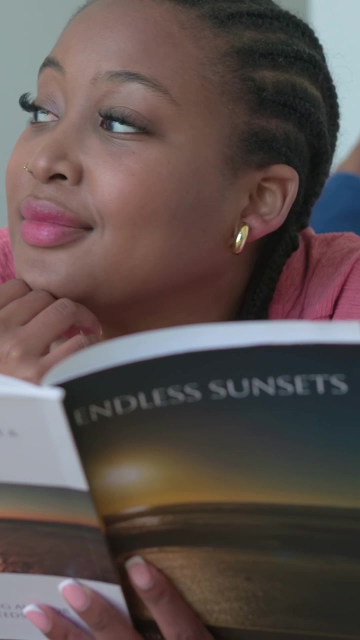 Video verticale: Donna con maglietta rosa che apre un libro e sfoglia le pagine sul letto per rilassarsi con TRAMONTI INFINITI