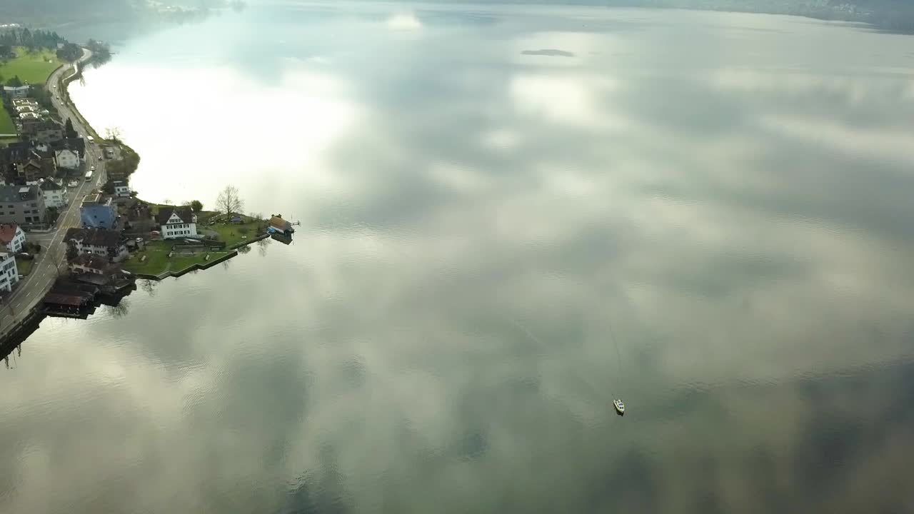 보트는 스위스 추크에 있는 매우 반사적인 호수에 있습니다.