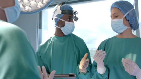 diverse female and male surgeons in masks in discussion during operation, slow motion