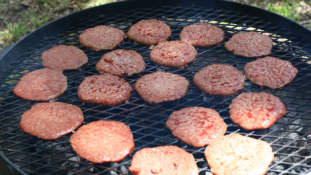 Large grill with many burgers being cooked on an outside