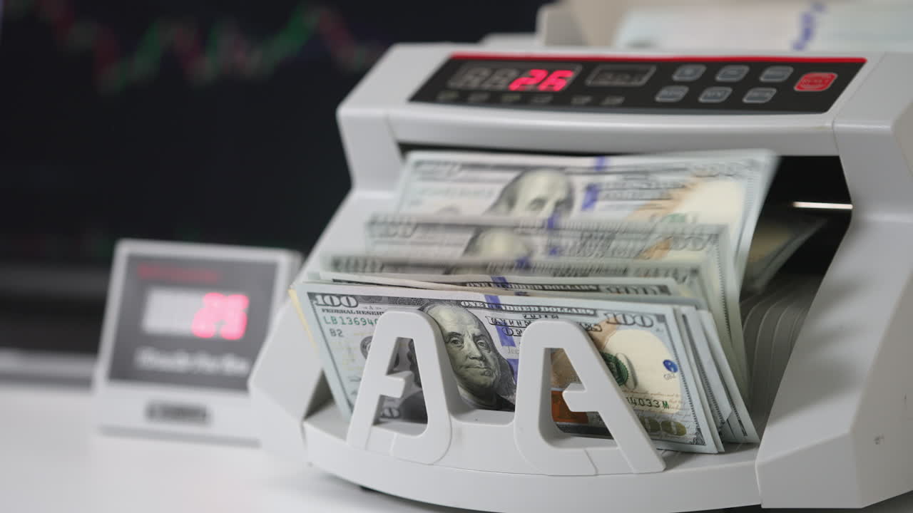 White compact cash counting machine working. One hundred dollar bills being turned in the counter. Close up.