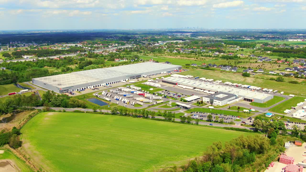 세미트레일러가 있는 트럭은 적재 허브가 있는 물류 공원의 주차장에 서서 일몰 시 창고 경사로에서 화물을 싣고 내리기를 기다립니다.