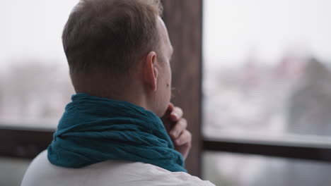 man gazes upon winter through window. mature gentleman engages in profound contemplation relishing tranquility afforded by calm solitude at home