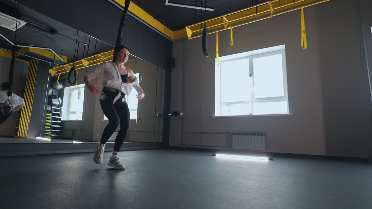 여성 운동 선수 는 운동 을 위해 trx 시스템 을 사용 하여 서스펜션 훈련 을 연습 하고 있다