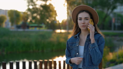 young woman talking on phone in park at sunset