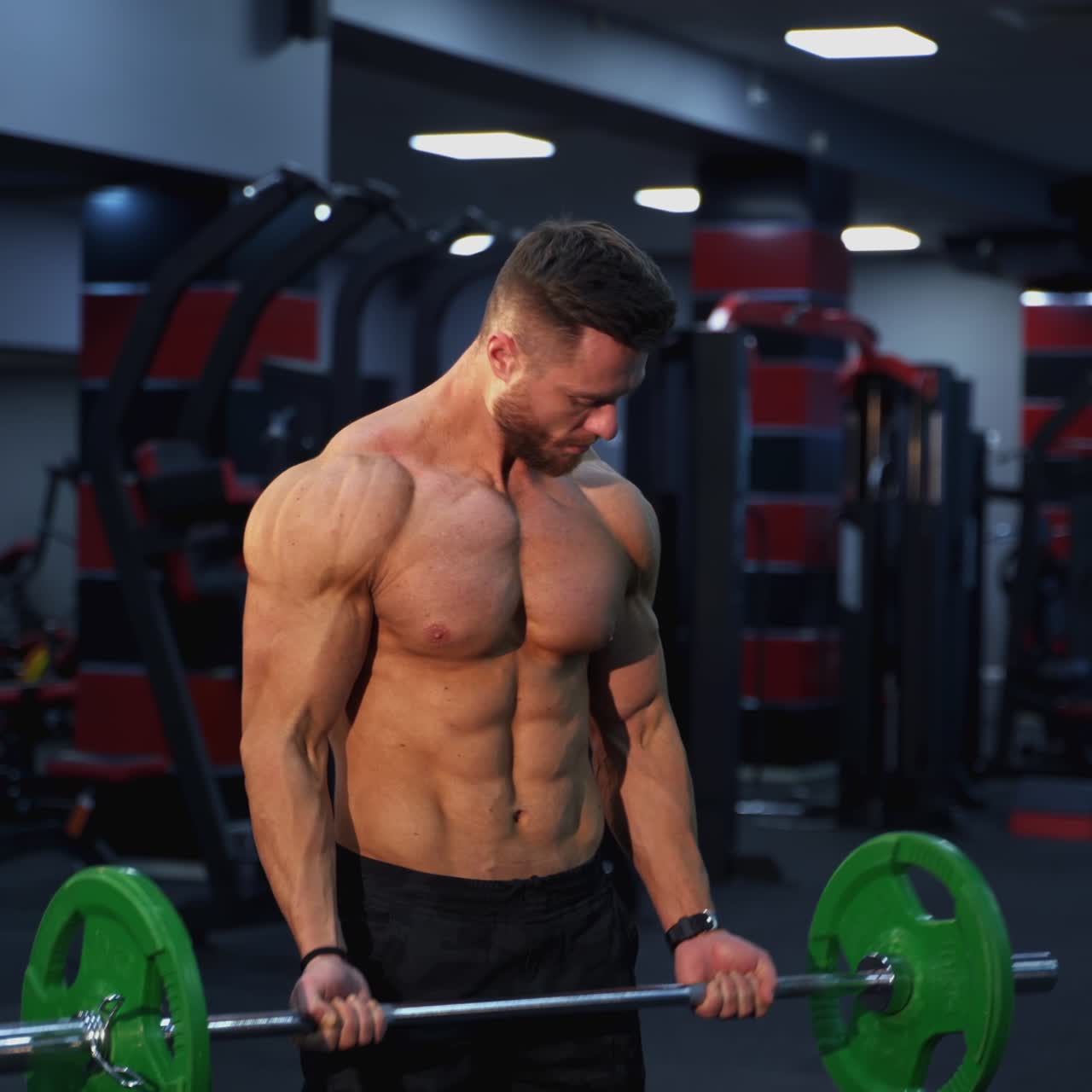 Strong athlete lifting barbell in gym. Handsome man doing exercise with a heavy barbell. Sportsman doing strength and endurance exercises with barbell. Weightlifting