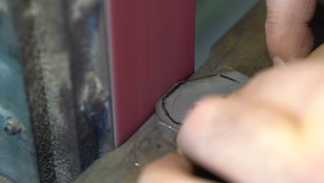 sanding belt used to grind metal part for creating furniture joint, close up handheld shot