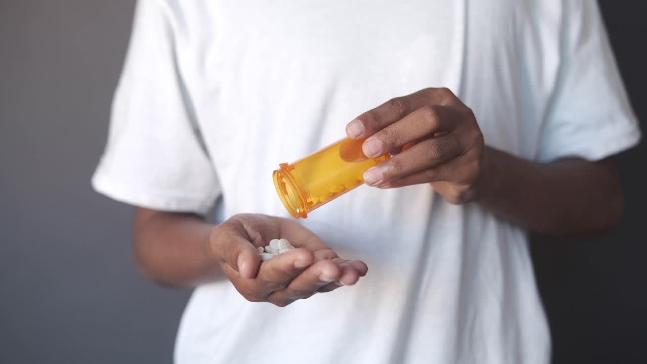 persona vertiendo pastillas de un recipiente en su mano