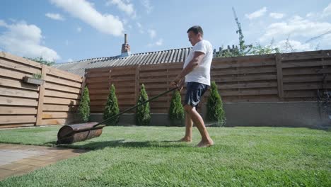 gardener laying a roll of natural lawn turf