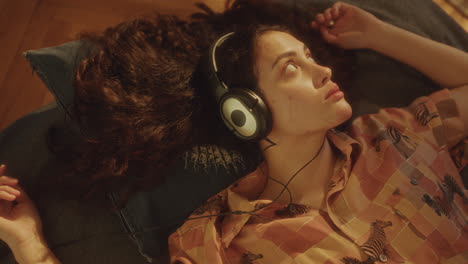 relaxed girl with headphones lying on bed in sunlit room