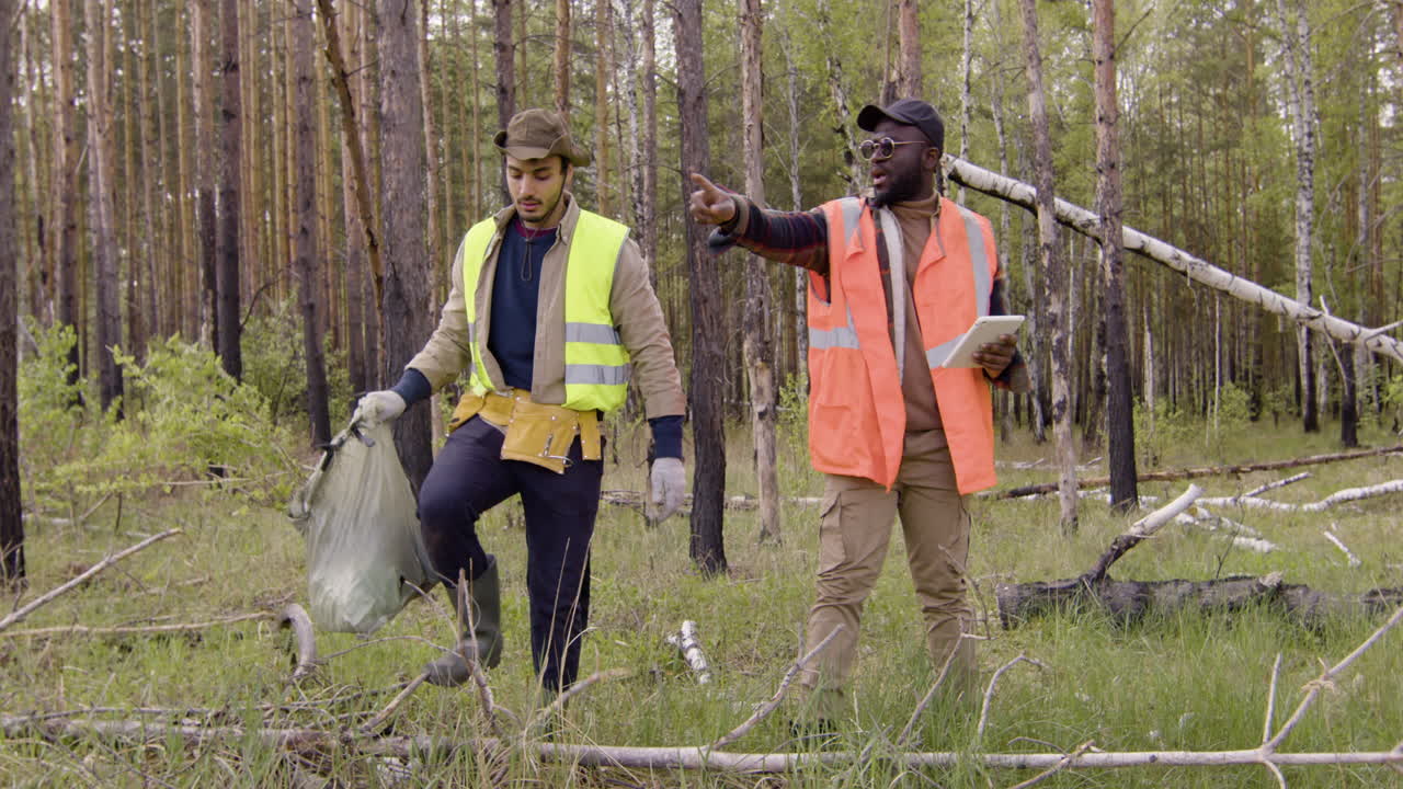 Caucasian man activist carrying small trees in a sack and african american man holding a tablet