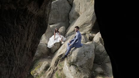 Groom-with-bride-sit-on-a-high-slope-of-the-mountain.-Wedding-couple.-Happy