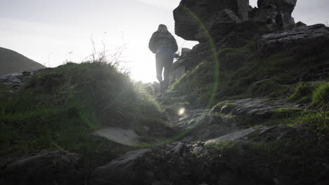 woman climb and hike at the valley of the rocks backlit by the sunlight in lynton, england, united kingdom