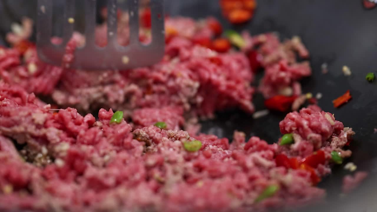Close-up of beef stir fry preparation with vegetables in a pan. Vibrant colors and dynamic cooking action