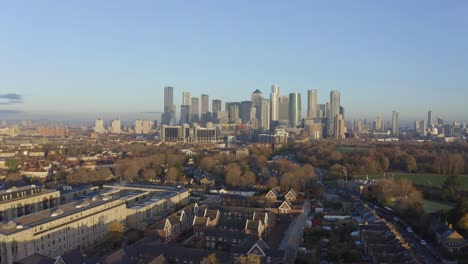 rising drone shot from residential buildings to canary wharf skyscrapers at sunrise