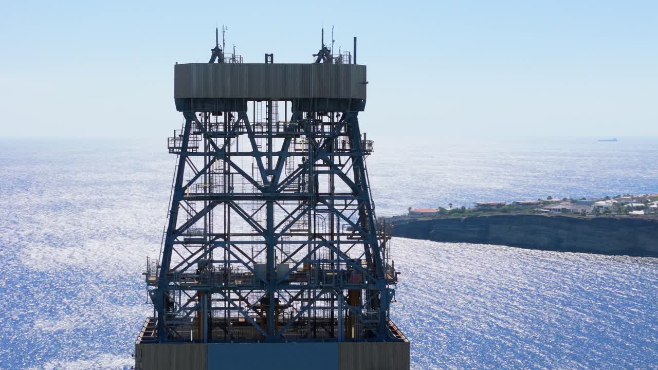 Aerial close-up of oil rig platform towers with surrounding calm blue ocean, near the Caribbean coast