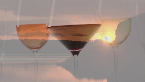 composite of glasses of white, rose and red wine over sunset background