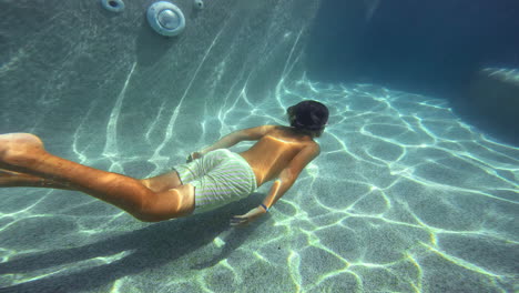 cámara lenta - un adolescente nadando en una piscina bajo el agua