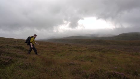 un excursionista cruzando un pantanoso paisaje de brezos en escocia