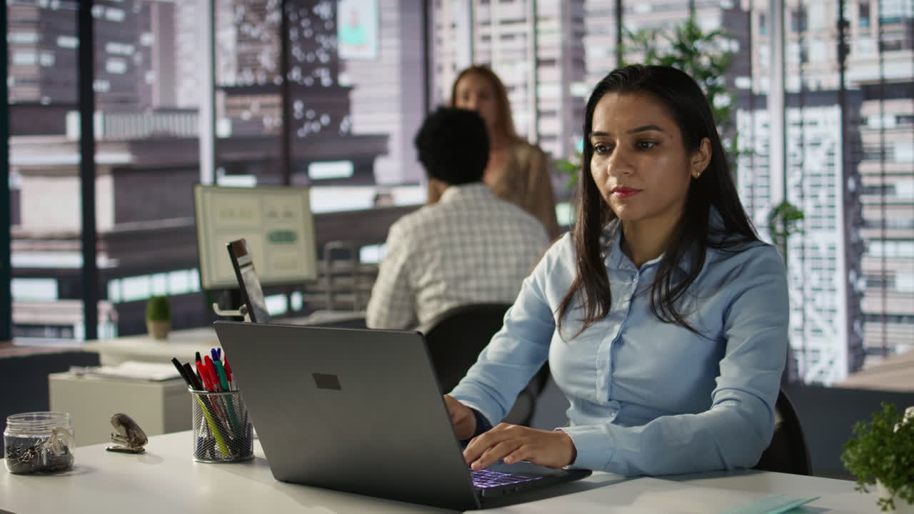Woman working on laptop in office with colleagues