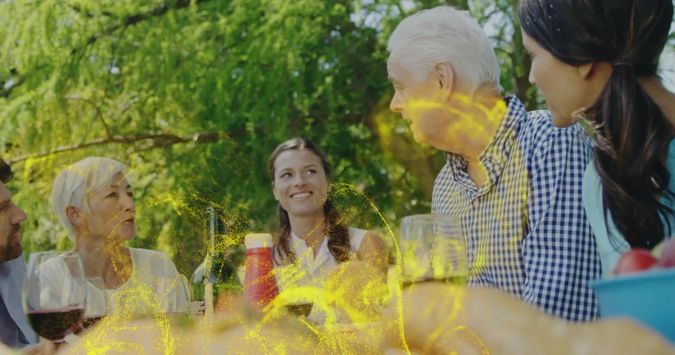Senior man turning to relatives, telling story for bonding in picnic ad, golden sparkles swirling
