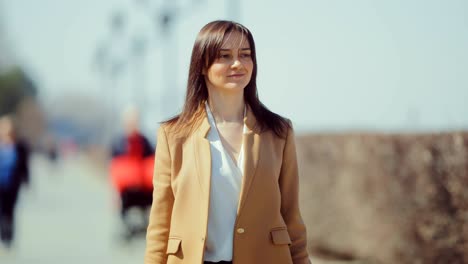 beautiful young woman walks along the paths of the park and enjoys life. pretty girl walks and touches hair with her hand. circular motion of the camera.