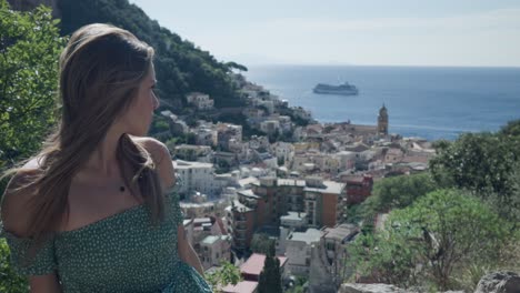 front view of a gorgeous woman at viewpoint in amalfi coast overlooking mediterranean coastline and seascape in italy