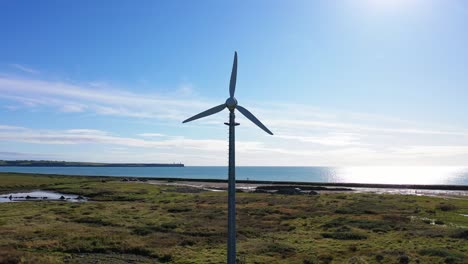 Turbina-Eólica-En-Medio-Del-Campo-Verde-En-Irlanda,-Fondo-Azul-Del-Mar