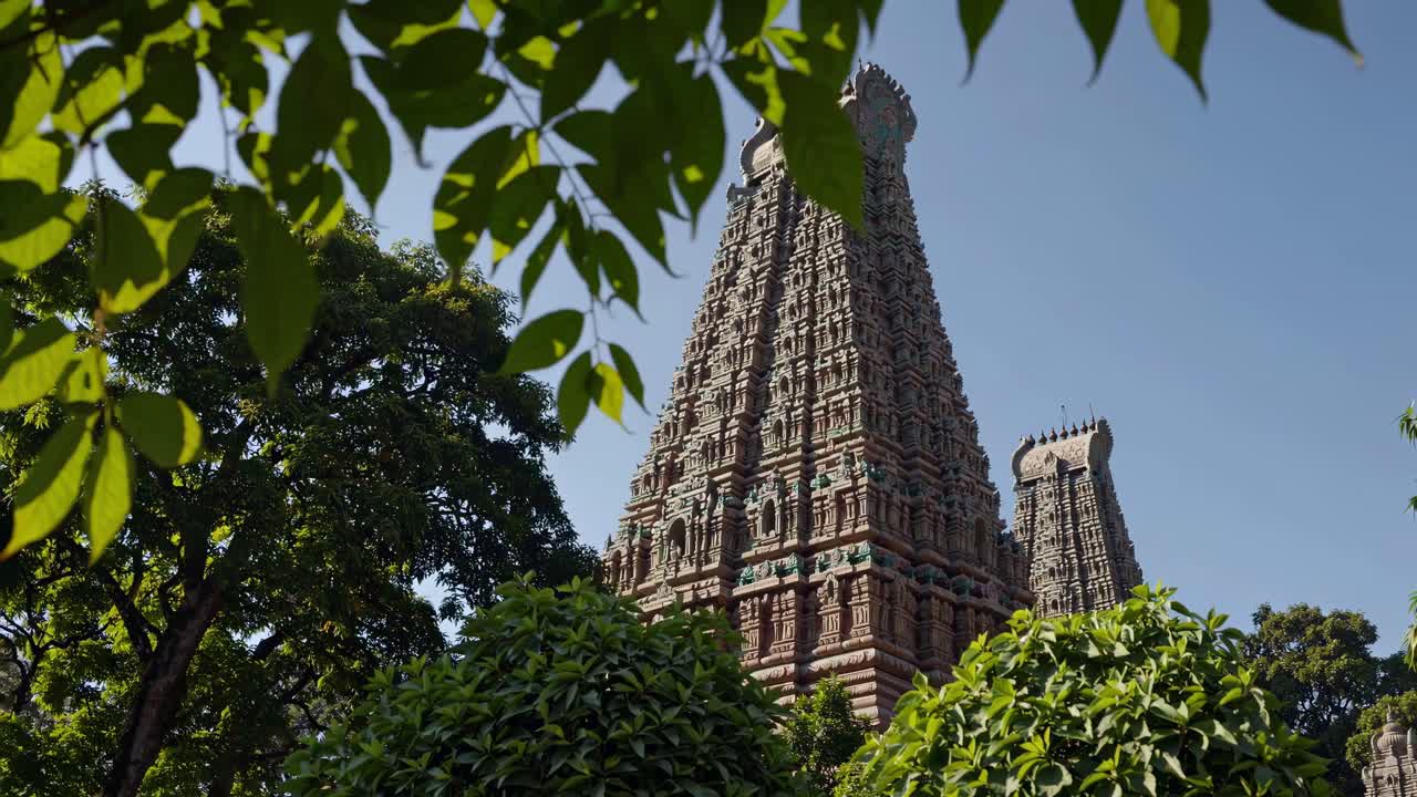 Low-angle shot of ornate temple towers framed by lush greenery, capturing the intricate