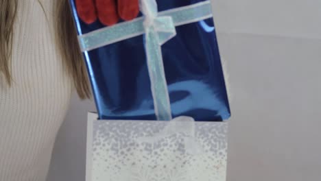 Hand wearing Santa gloves with Christmas gift medium shot