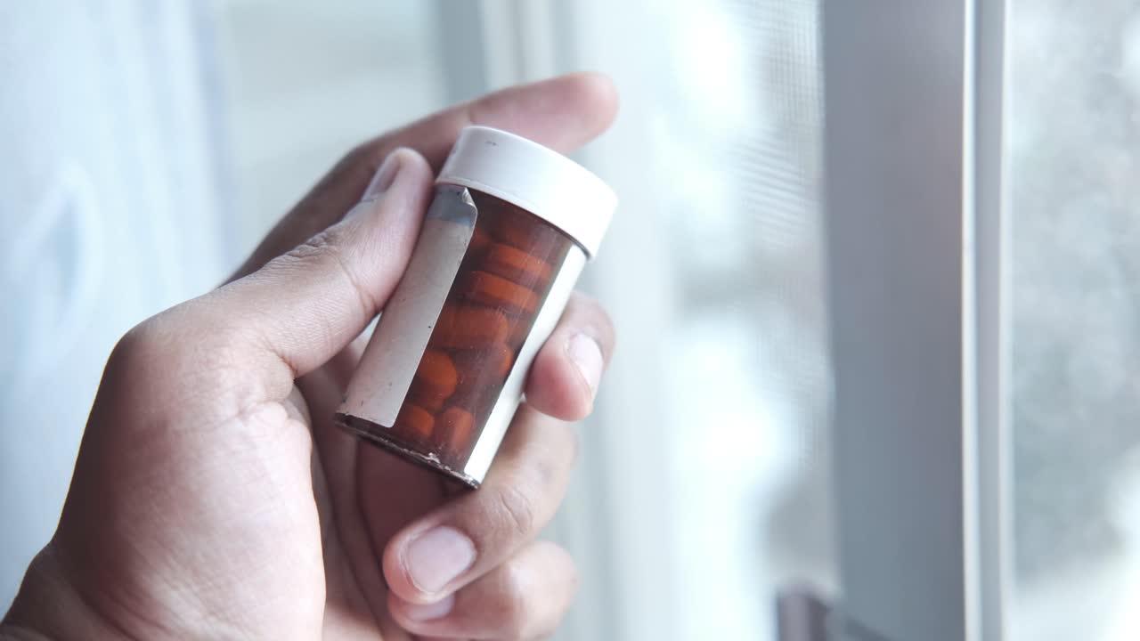 창문 근처에 약병 병을 들고 있는 손