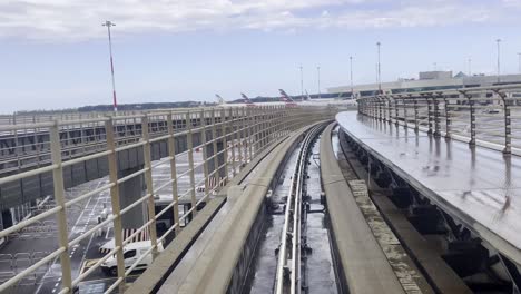 first view of skybridge monorail train moving along a curved track, linking the satellite terminal to the main terminal at rome fiumicino airport, italy