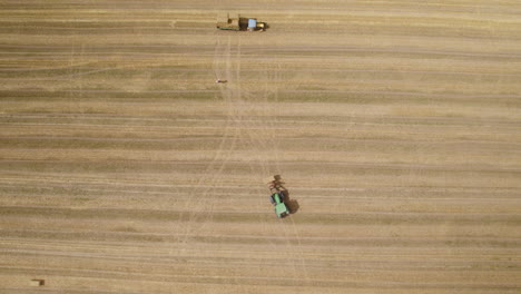 Ein-Grüner-Traktor,-Der-Das-Feld-überquert-Und-Einen-Quaderballen-Heu-Trägt,-Um-Ihn-Auf-Einen-Wagen-Zu-Laden