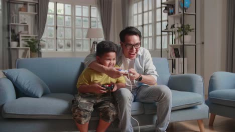 asian man and son win playing video game, hands up while winning video game