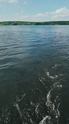 waves are formed on the river after the boat. view of the bank from the boat. weekend walk on the river vertical video