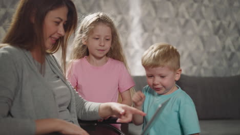 mother and sister watch toddler pushing buttons on keyboard