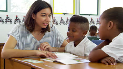 volunteer teacher helps young school kids in class, close up