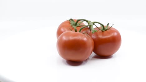 tres tomates rojos en un armazón girando sobre una superficie blanca